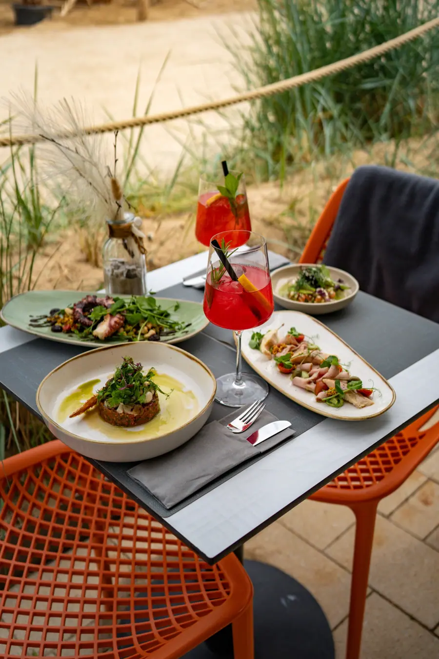 Gedeckter Tisch mit Spritz und Gerichten am Strand