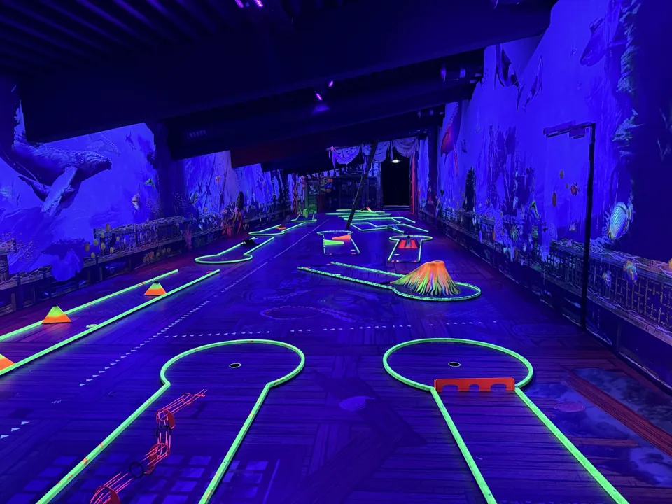 Schwarzlicht-Minigolf-Halle mit Neon-Bahnen, Vulkan und Unterwasser-Wandbildern