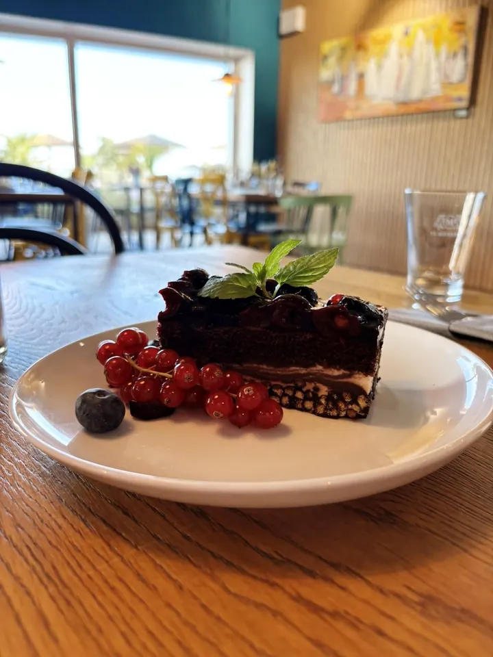 Schokoladentorte mit Beeren und Blick durchs Fenster auf den Beach